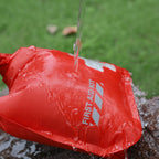 Red first aid kit being rinsed with water against a green background