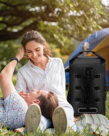 Woman and man lying on grass with a black idrybag waterproof drybag in the foreground